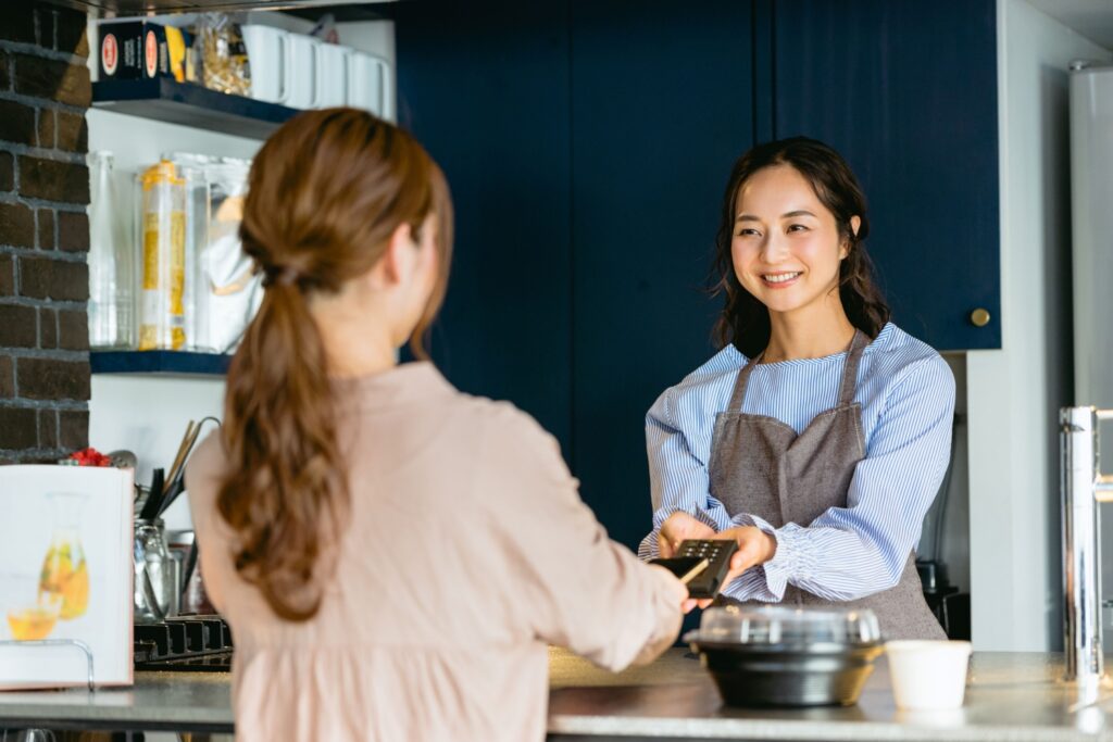 カフェのレジでスマホ決済する女性