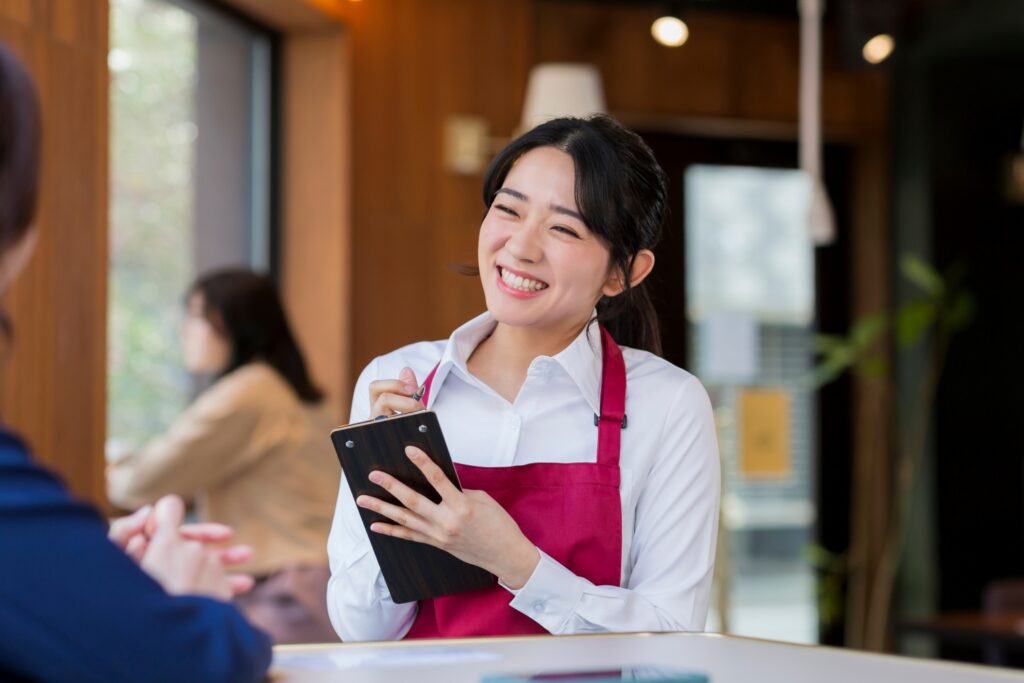 カフェで注文を取る笑顔な女性店員