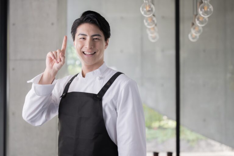 エプロンを着たシェフや飲食業で働く男性のイメージ　指さしのポイント