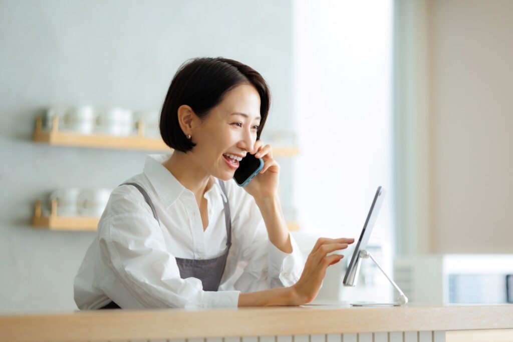 電話しながらタブレットで予約を確認するカフェ店員