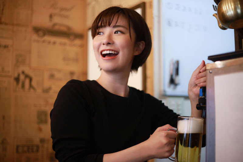ビールを注ぎながら接客する居酒屋店員